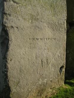 Gravures de l'âge du bronze. Sous l'inscription horizontale du XVIIe s., on distingue : à gauche, un poignard ; à droite, une tête de hache, le tranchant vers le haut ; on devine d'autres armes.