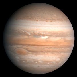 La planète Jupiter, photo prise par la sonde Voyager. Le cyclone appelé "grande tache rouge" est visible sur la gauche, un peu en dessous de l'équateur.